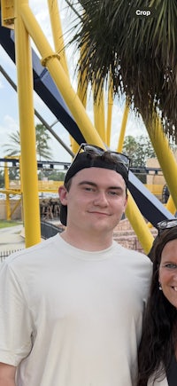 a man and woman posing for a photo in front of a roller coaster