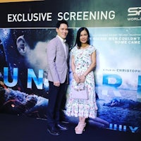 a man and woman standing in front of a movie poster