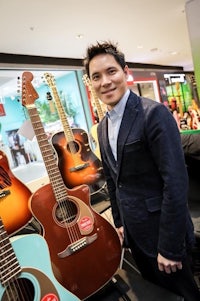 a man standing in front of a display of guitars